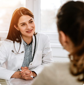 alt="Smiling female orthopedic doctor in a white coat listening attentively to a patient during a consultation."