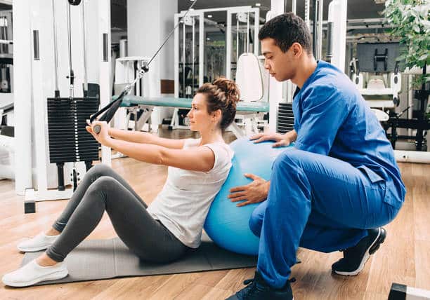 kinesiologist helps a woman do exercises to strengthen her back muscles. treatment of back pain with kinesitherapy.