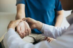 Physical therapist checks the patient wrist Pain by pressing the wrist bone