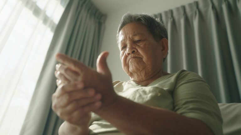 A senior woman at home is experiencing hand pain due to arthritis.