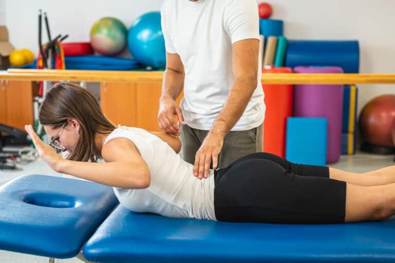 A woman performing back extension stretch exercises during her physical therapy for degenerative disc disease with her therapist.