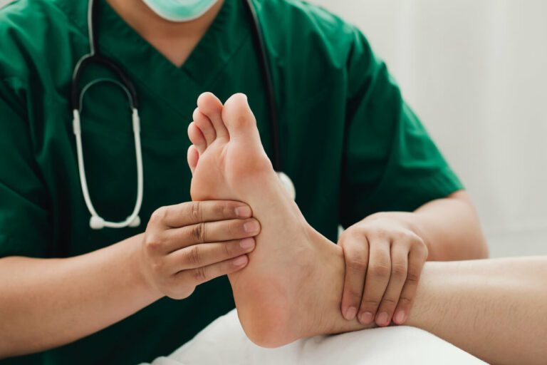 A male sports foot doctor wearing a nose mask is examining the feet of a runner who is in pain.