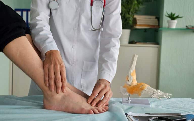 A podiatrist conducting an ankle examination on a patient who has arthritis in their feet and ankles.