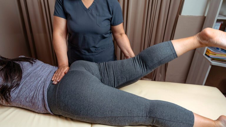 Physical therapist assisting young woman with physical therapy for hip pain.