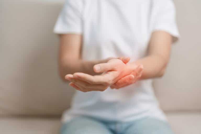 Woman having wrist pain while sitting on sofa at home.