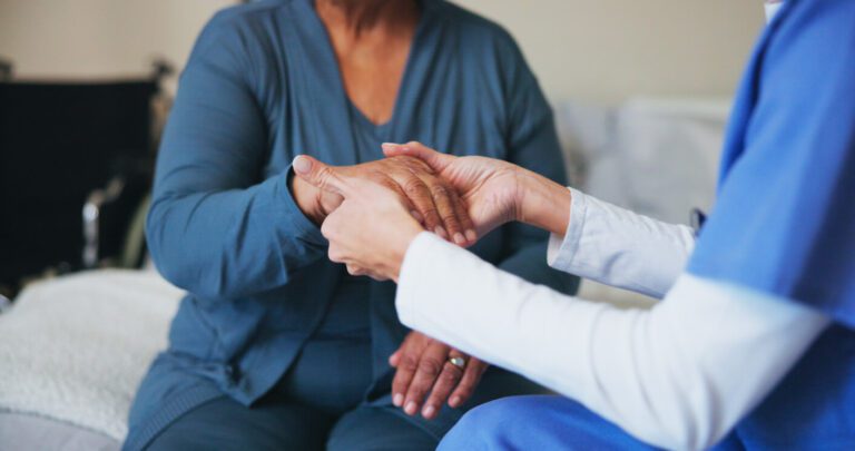 A therapist carefully evaluates an elderly patient showing symptoms of carpal tunnel syndrome.