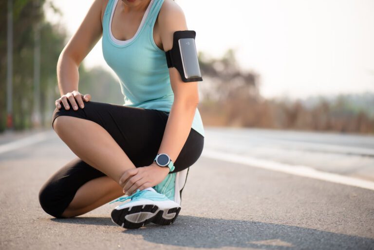 Young woman suffering from an sprained ankle injury while exercising and running.