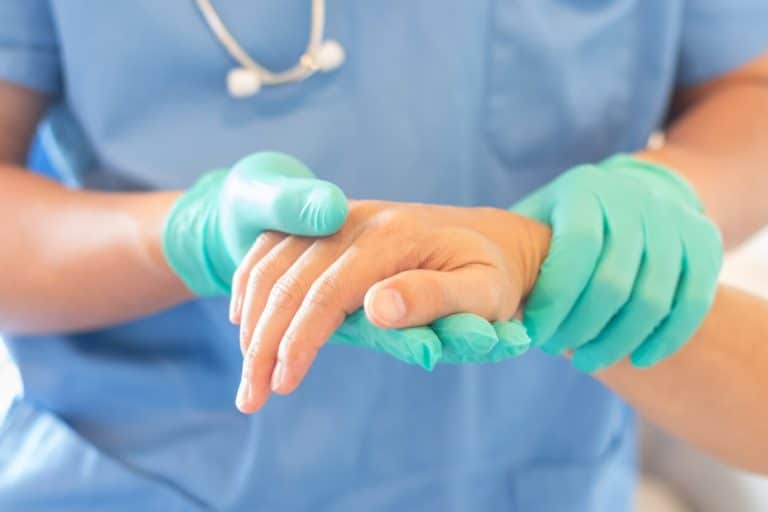 A specialist in hand surgery​ is holding patient's hand for health care trust and support in professional ER surgical operation.