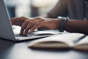 A close up of a man's hands typing on the keyboard as he is dealing with unruly hand pain.