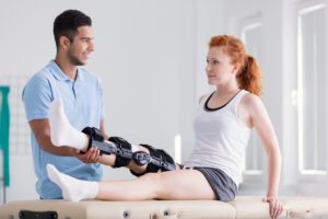 Young woman wearing a brace during rehabilitation with her physiotherapist