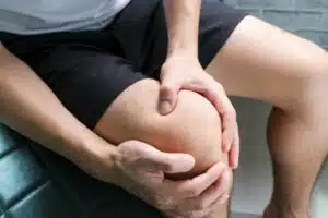 Knee pain .man sitting on the bed Her hand caught at the knee. Having painful feet and stretching muscles fatigue To relieve pain. health concepts.