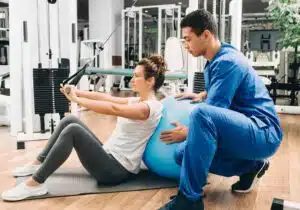 kinesiologist helps a woman do exercises to strengthen her back muscles. treatment of back pain with kinesitherapy.