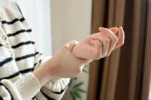 Young woman experiencing symptoms of carpal tunnel in her wrist.