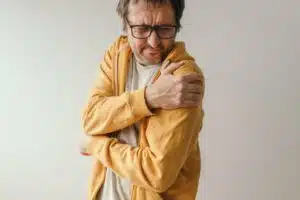 Adult Caucasian male experiencing aching pain in a frozen shoulder as a symptom of rotator cuff tendinitis.