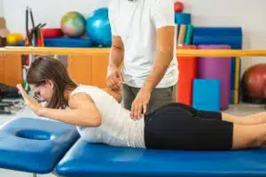 A woman performing back extension stretch exercises during her physical therapy for degenerative disc disease with her therapist.