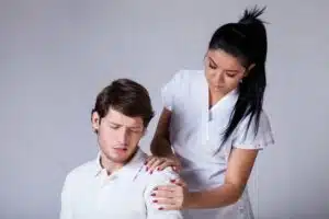 A male patient is receiving physical therapy for painful shoulder due to rotator cuff tears from a female physical therapist.