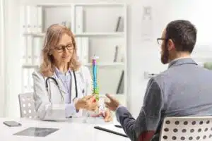 A man is at a hospital appointment with a female orthopedic doctor who specializes in back and spine.