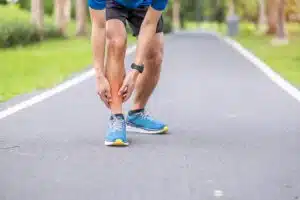 A young adult male is experiencing muscle pain in his shins due to shin splints while running.