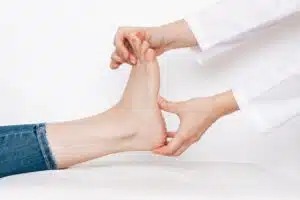 An image of a female orthopedist examining a young woman's feet for flat feet issues.