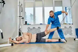 A young man receives guidance during recovery rehabilitation session with his sports medicine doctor at a medical facility.
