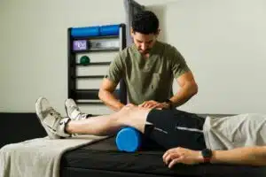 A therapist performing knee massage using foam roller during physical therapy for ACL tears.