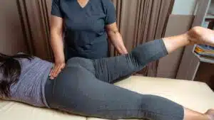 Physical therapist assisting young woman with physical therapy for hip pain.